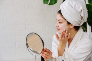 Young woman applying face mask at home. Natural Skin Care Routine. Cleaning face with natural cosmetics.